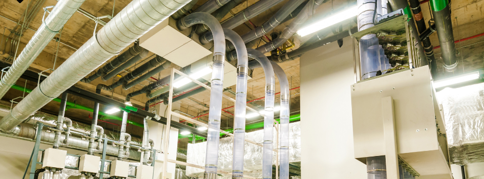 Pneumatic conveying system with vertical transfer tubes and overhead piping in an industrial facility