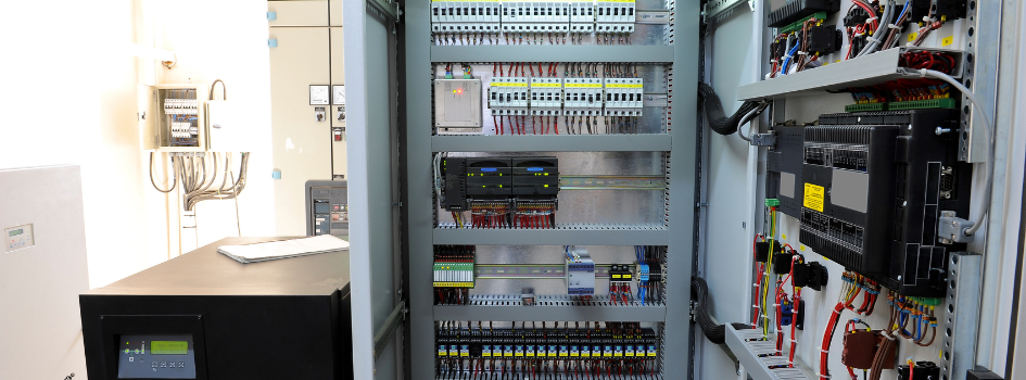 Industrial electrical control cabinet with PLCs and wiring, used to estimate VFD energy savings and motor speed control.